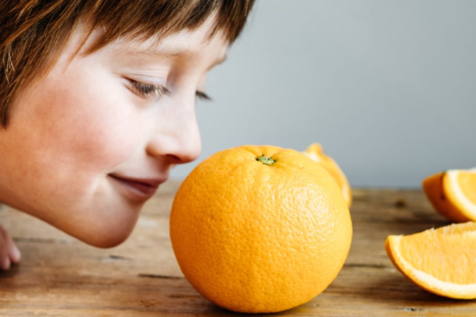 Boy Smelling Fresh Orange on wooden background