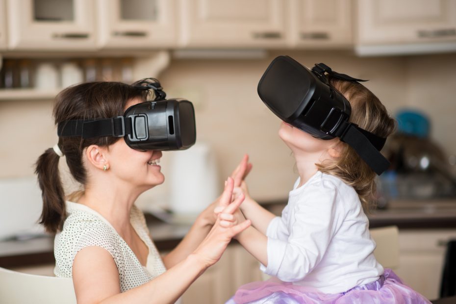 Mother and child playing together with virtual reality headsets indoors at home