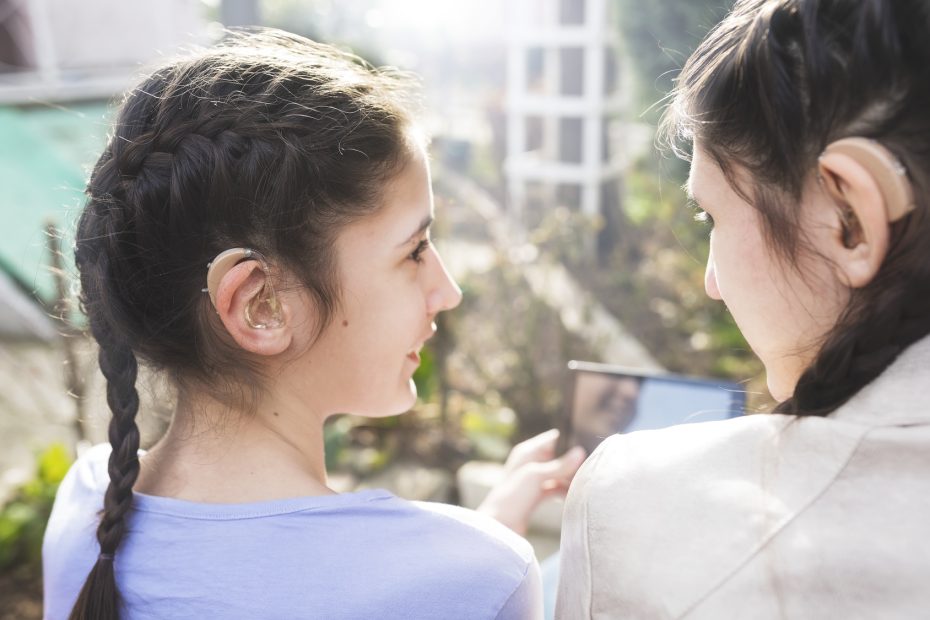 Teenage girls with hearing aid have a fun and use digital tablet