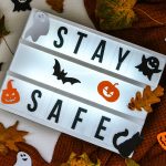 Stay safe. Text in white light box, with a background of sweater, dried leaves halloween autumn decoration. Coronavirus devices. Social distancing. Protection against pandemics. Cozy home