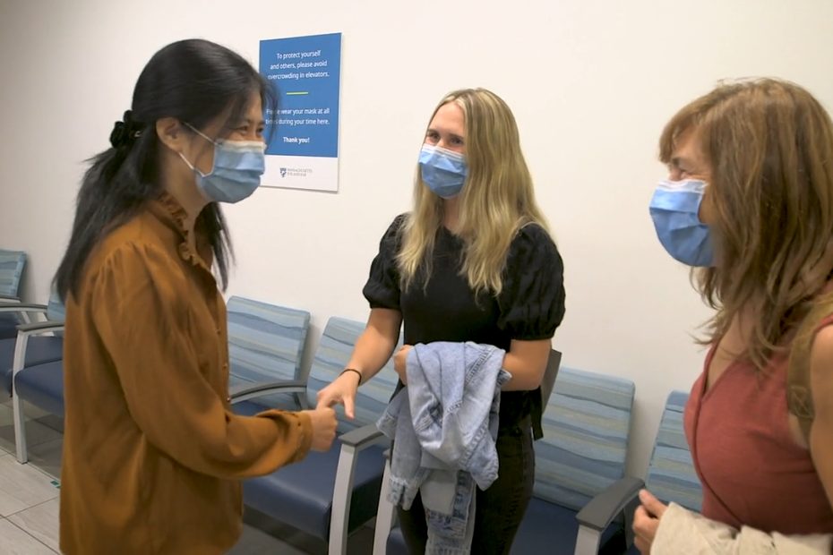 Photograph of Qin Liu, MD, PhD, shaking hands with Usher syndrome patient Hannah Corderman while Hannah's mother, Nancy, looks on.