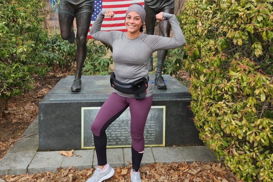 Leslie Pascual-Esposito poses with her arms up after a recent run in in front of the Johnny Kelley marathon statue in Newton, Massachuestts.