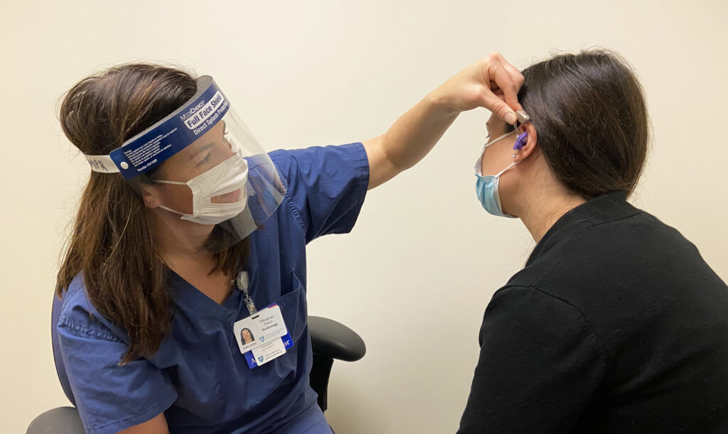 Meaghan Reed, AuD, CCC-A, fits a patient with a hearing aid at Mass Eye and Ear.