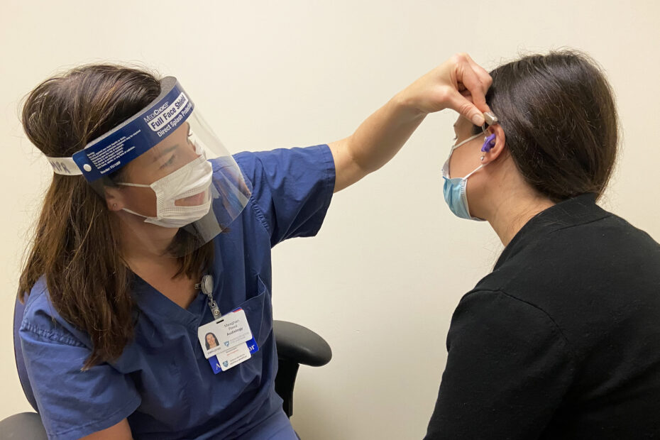 Meaghan Reed, AuD, CCC-A, fits a patient with a hearing aid at Mass Eye and Ear.