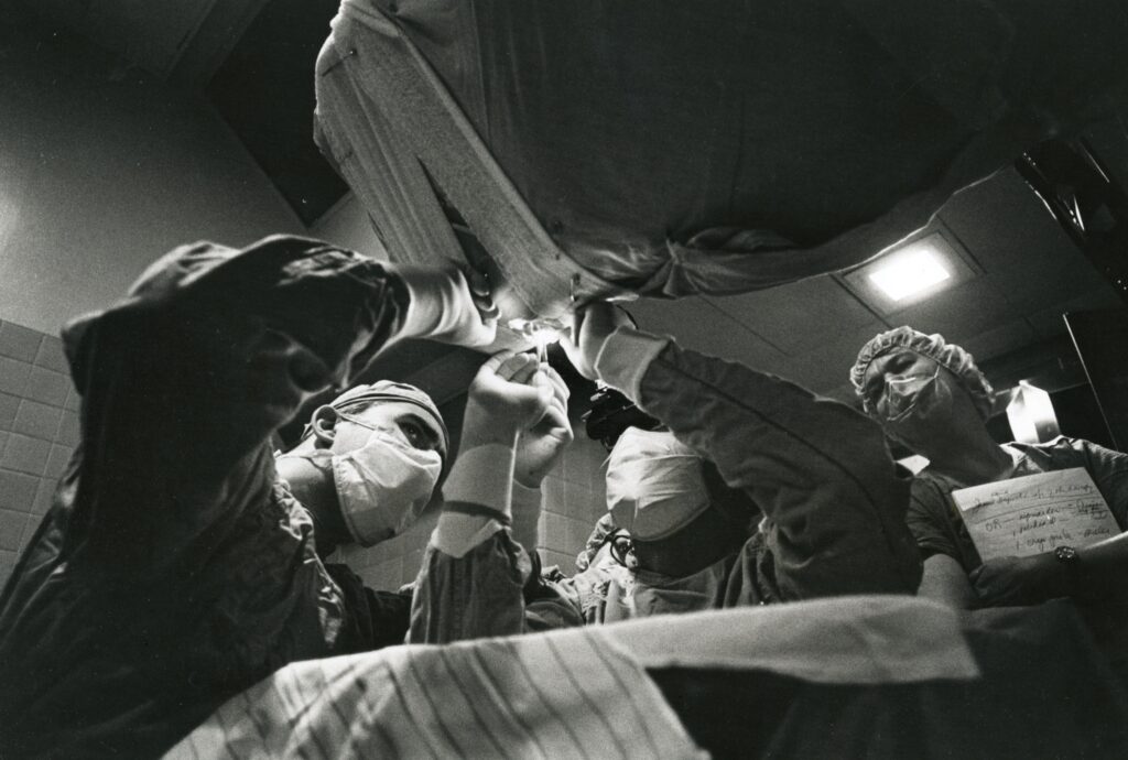 Retinal surgeons operate on a patient using the inverted operating table designed by Drs. Hal Freeman and Charles Schepens. Date of photo unknown.