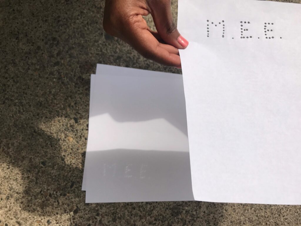 A piece of paper used to make a pinhole eclipse projector using the Mass Eye and Ear initials