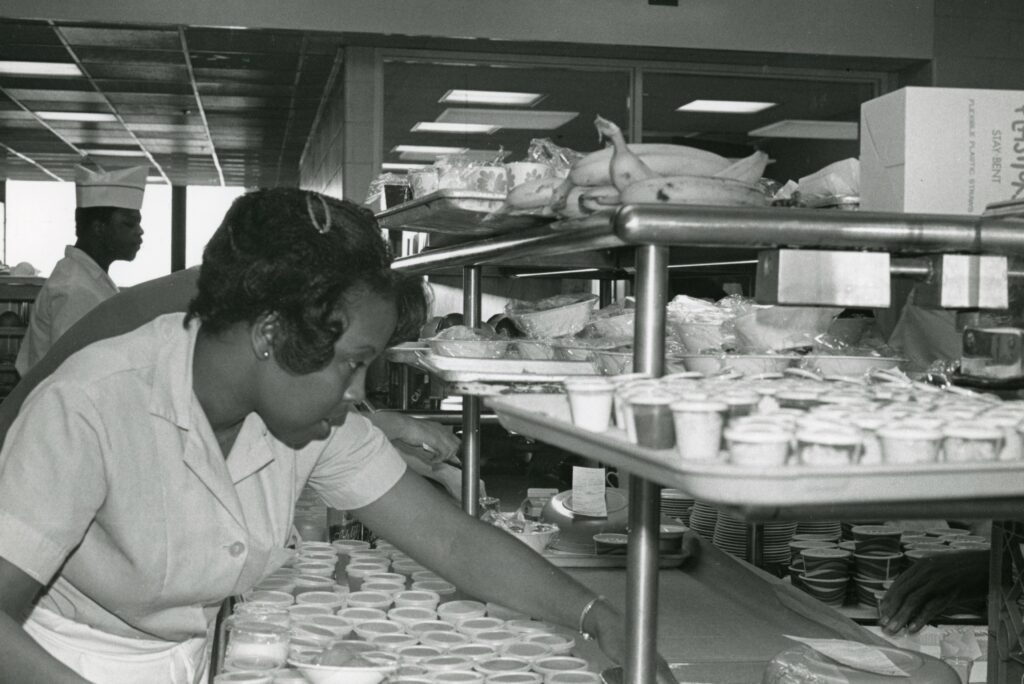 Ethel Hargrove reaches for a tray as she prepares dessert in the cafeteria, 1979.