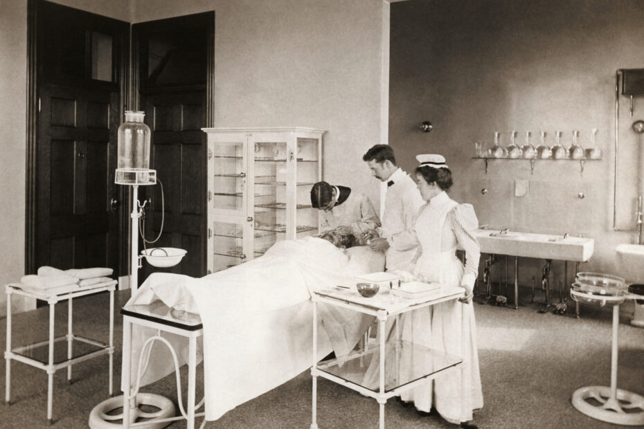 A nurse (far right) assists two physicians in the eye clinic, circa 1900 in this historical black and white photo.