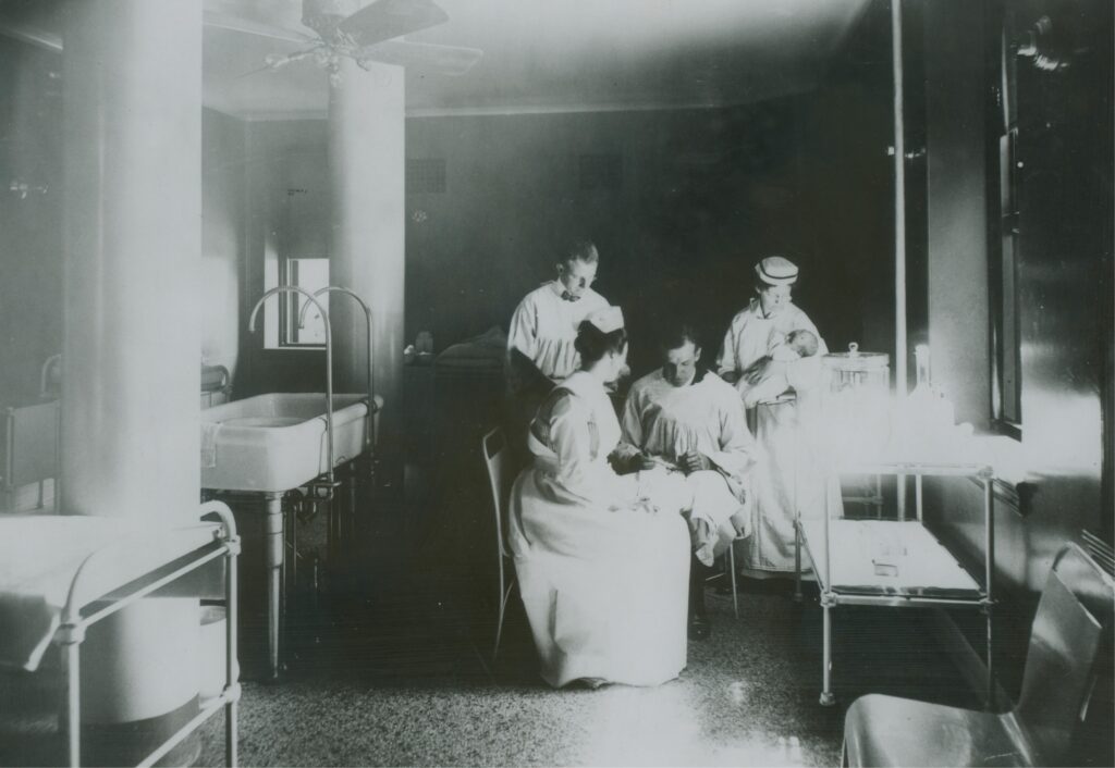 Nurses and physicians treat pediatric patients in the Gardner Building, 1915