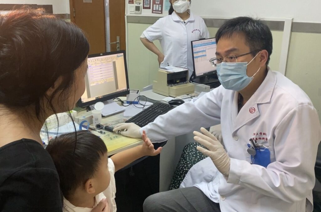 Dr. Yilai Shu communicates with a mother holding her child patient at the Eye & ENT Hospital of Fudan University