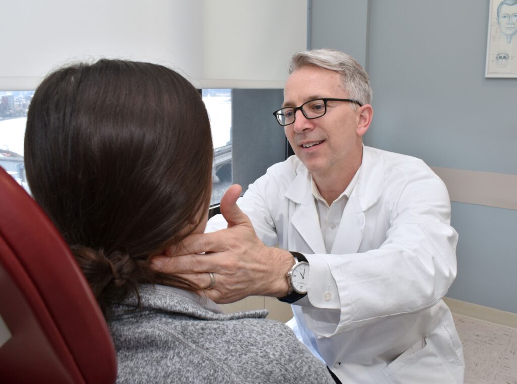 Kevin Emerick, MD, examines a patient's neck at Mass Eye and Ear